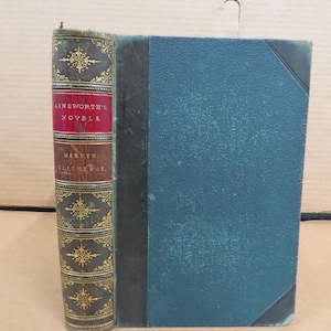 May include: Antique hardcover book titled "Ainsworth's Novels" with a teal cover and decorative spine. The spine is brown and gold with the title and author's name. The book's cover is teal with a black border. The book is in good condition.