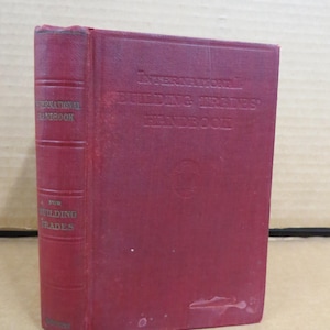 May include: A maroon-colored book titled "International Building Trades' Handbook." The book's spine reads "International Handbook" and "For Building Trades." The cover and spine show signs of wear.