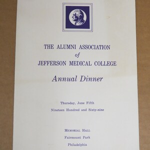 May include: A vintage invitation for the Jefferson Medical College Alumni Association Annual Dinner. The invitation is white with blue text and a blue emblem. The text includes the date, location, and event details.