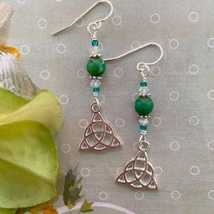 May include: Silver earrings with a green stone and a silver Celtic knot design.