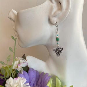 May include: Silver Celtic knot earrings with a green gemstone bead and silver beads.