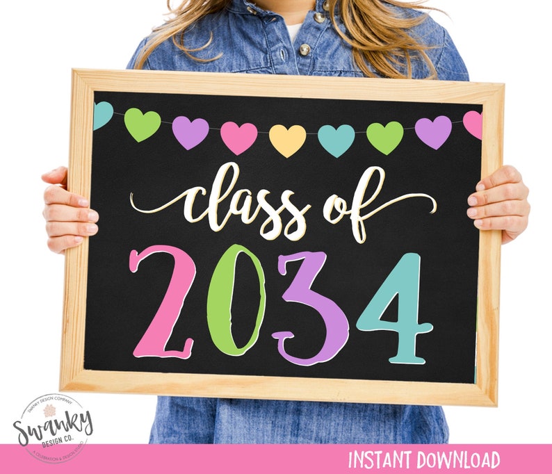 May include: A chalkboard sign with a wooden frame, decorated with a colorful heart garland. The sign reads "Class of 2034" in a whimsical font with each number in a different color.