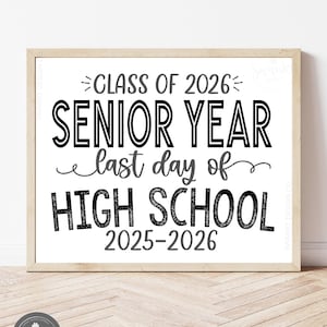 May include: A framed print with the text "CLASS OF 2026 SENIOR YEAR last day of HIGH SCHOOL 2025-2026" in black and gray. The print is in a light wood frame and sits on a light wood surface. The bottom right corner reads "INSTANT DOWNLOAD ~ COMES WITH GRADE SHOWN."