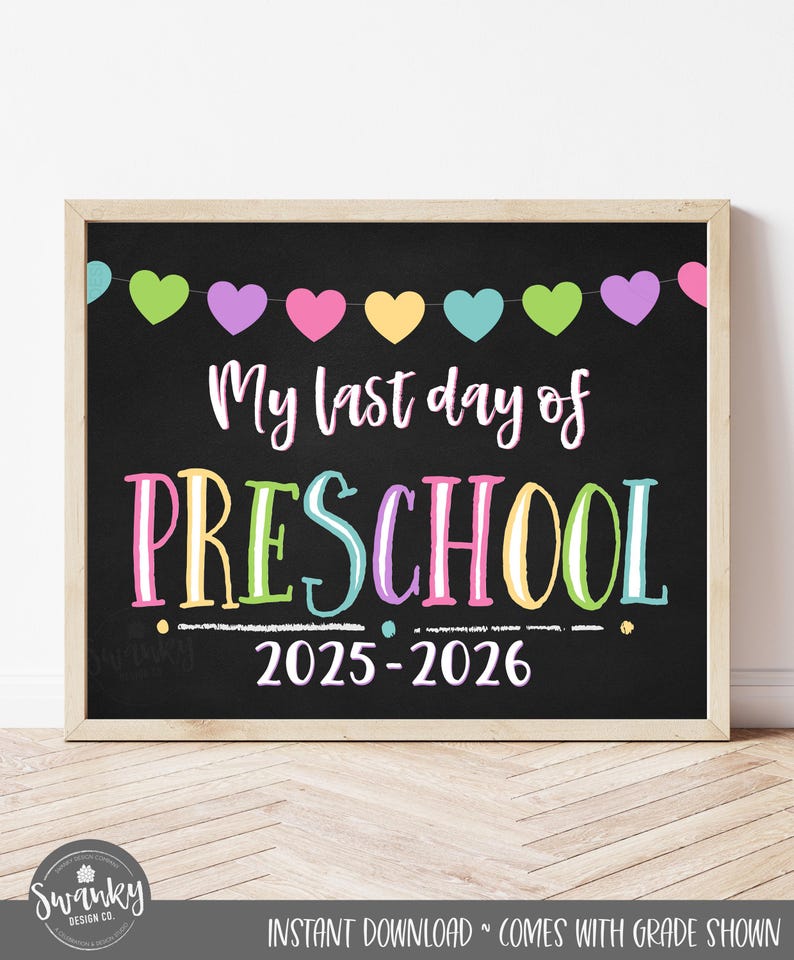 Op de afbeelding: Een ingelijst schoolbordbord met de tekst "My last day of PRESCHOOL 2025-2026". Het bord heeft een zwarte achtergrond, kleurrijke tekst en een slinger van harten bovenaan. De lijst is lichtbruin.