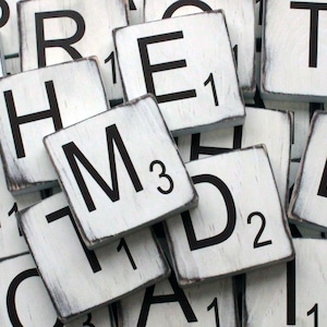 May include: White wooden tiles with black letters spelling out the word "REMTED" with the letter "M" having a value of 3. The tiles are worn and have a distressed look.