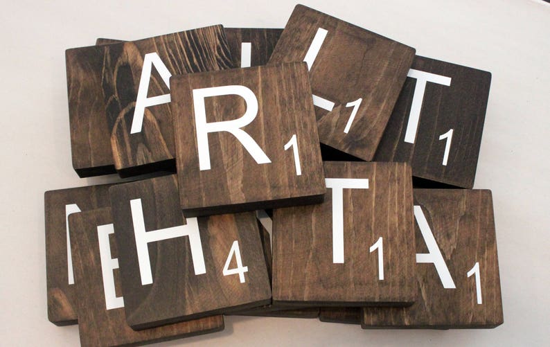 May include: A set of wooden Scrabble tiles with the letters "ART HEART" spelled out. The tiles are brown with white lettering and have a rustic look.