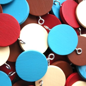 May include: A garland of wooden circles in red, blue, and cream colors. The circles are connected with silver wire loops.