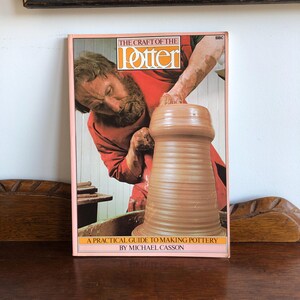 May include: A book titled "The Craft of the Potter" with a pink border. The cover shows a potter shaping clay. The text "A Practical Guide to Making Pottery by Michael Casson" is at the bottom. The BBC logo is in the top right corner.