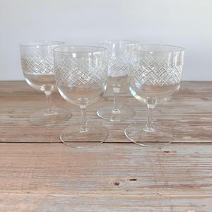 May include: A set of four clear glass goblets, each featuring a delicate diamond-cut crosshatch pattern etched around the upper bowl. The glasses have a smooth, rounded rim, a slender stem, and a circular base, providing a uniform appearance.