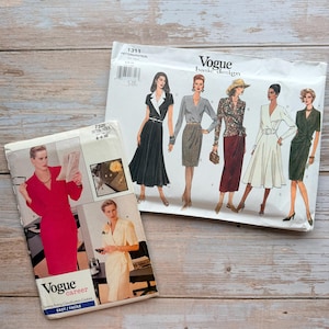 May include: Two Vogue sewing pattern envelopes. One envelope, number 7321, displays a red dress and a cream dress. The second envelope, number 1311, features illustrations of five different dress styles in black, grey, floral, white, and dark green.