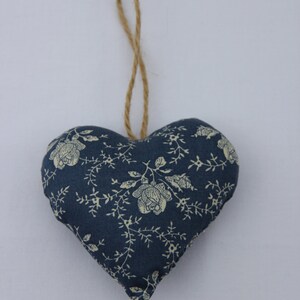May include: A blue fabric heart with a white floral pattern, hanging from a brown twine string.