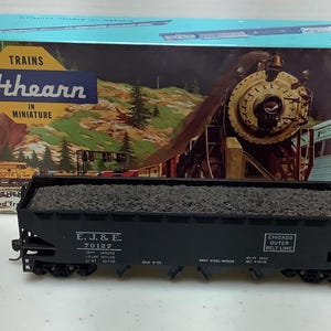 May include: Athearn model train set featuring a black coal car with the text "E.J. & E." and "Chicago Outer Belt Line." The box behind the car displays a train illustration and the words "Trains in Miniature."