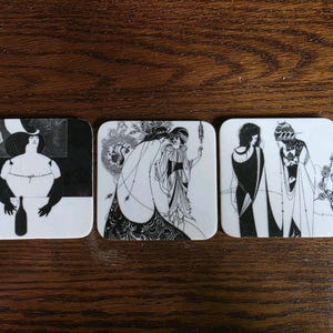 May include: Three square coasters featuring black and white line art illustrations. The first shows a figure at a table with a bottle, the second depicts two figures in flowing garments, and the third displays two figures in long robes with floral details.