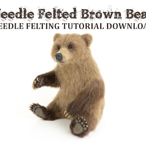 Puede incluir: Un oso marrón de fieltro de aguja sentado sobre un fondo blanco. El oso tiene un pelaje marrón claro con acentos marrones más oscuros alrededor de los ojos y la nariz. El oso está sentado con las patas metidas debajo del cuerpo. El texto "Needle Felted Brown Bear" y "Needle Felting Tutorial Download" es visible en la parte superior de la imagen.