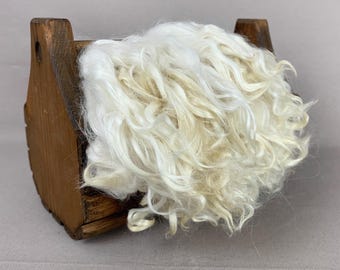 May include: A wooden box with a hinged lid, filled with a large amount of white curly sheep wool.
