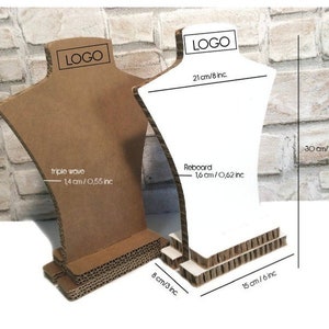 Op de afbeelding: Twee kartonnen halsketting display bustes, &eacute;&eacute;n bruin en &eacute;&eacute;n wit. De bruine buste heeft een drievoudig golfontwerp, 1,4 cm dik. De witte buste is 21 cm breed en 30 cm hoog. Beide hebben een basis van 15 cm breed en 8 cm diep.