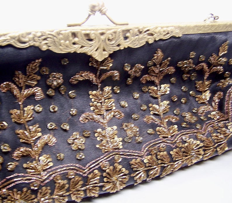 C) oblong clutch or handle bag, brass frame exstensive beading on front only, satin fabric, mirror inside and beaded chain handle.