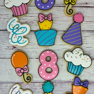 May include: A set of ten decorated sugar cookies featuring a birthday theme. The cookies are decorated with various colors, including purple, pink, yellow, blue, and orange. The cookies feature images of cupcakes, balloons, party hats, and the number eight.