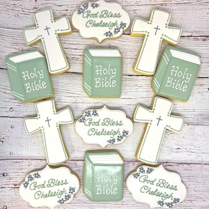 May include: Nine decorated sugar cookies with religious themes. The cookies are decorated with green and white icing and feature images of crosses, Bibles, and the text "God Bless Chelseigh" and "Holy Bible".