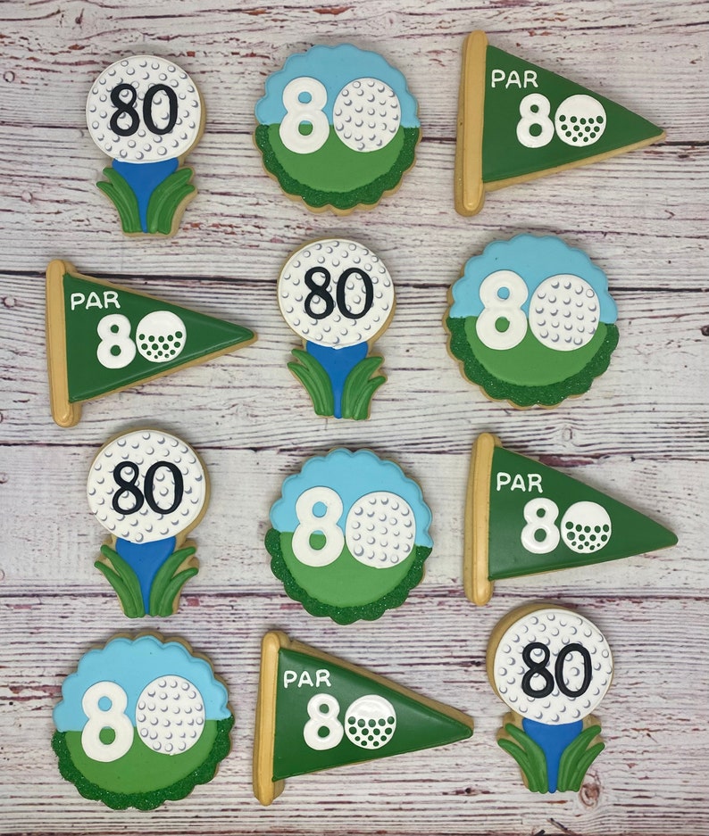 May include: Nine golf-themed sugar cookies decorated with green, white and blue icing. The cookies feature the number 80 and the word "PAR".