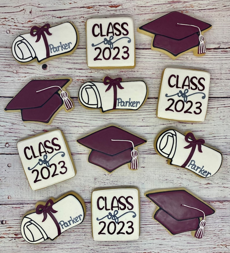 May include: Nine graduation-themed sugar cookies decorated with white icing and red and gray accents. The cookies feature the text "Class of 2023" and a graduation cap, diploma, and bow.