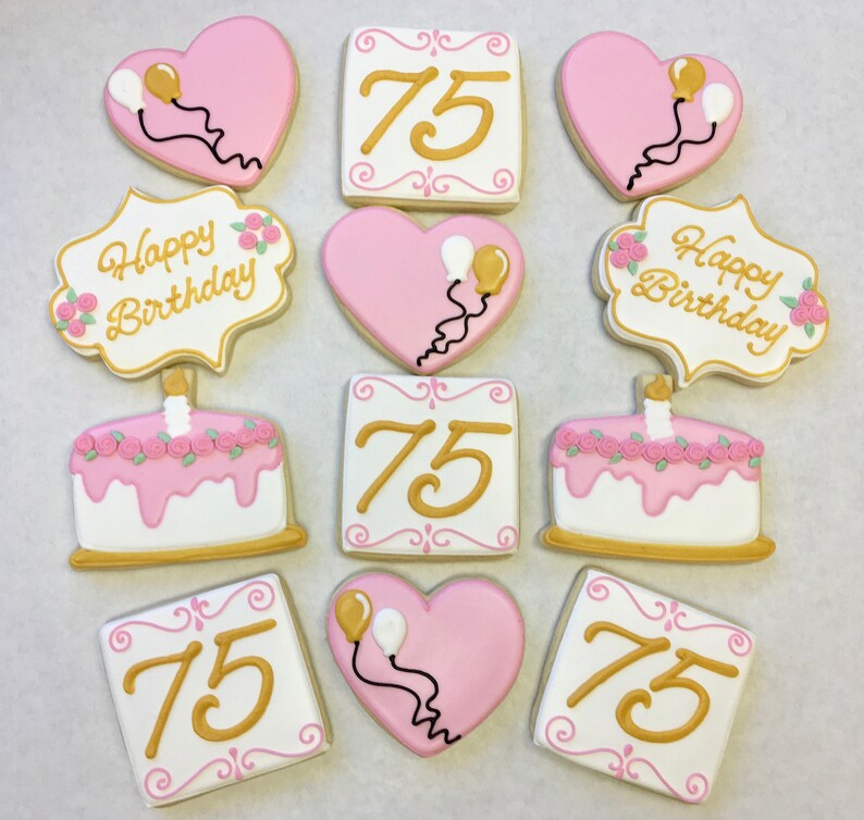 以下が含まれることがあります： ピンクとゴールドで飾られた砂糖菓子のセットです。クッキーはハート型、正方形、ケーキ型です。クッキーは数字の75、