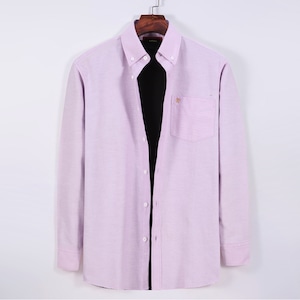Puede incluir: Camisa abotonada de color lila claro con mangas largas, bolsillo en el pecho y un peque&ntilde;o detalle bordado. La camisa est&aacute; colgada en una percha de madera sobre un fondo blanco. Tiene cuello cl&aacute;sico y pu&ntilde;os abotonados.