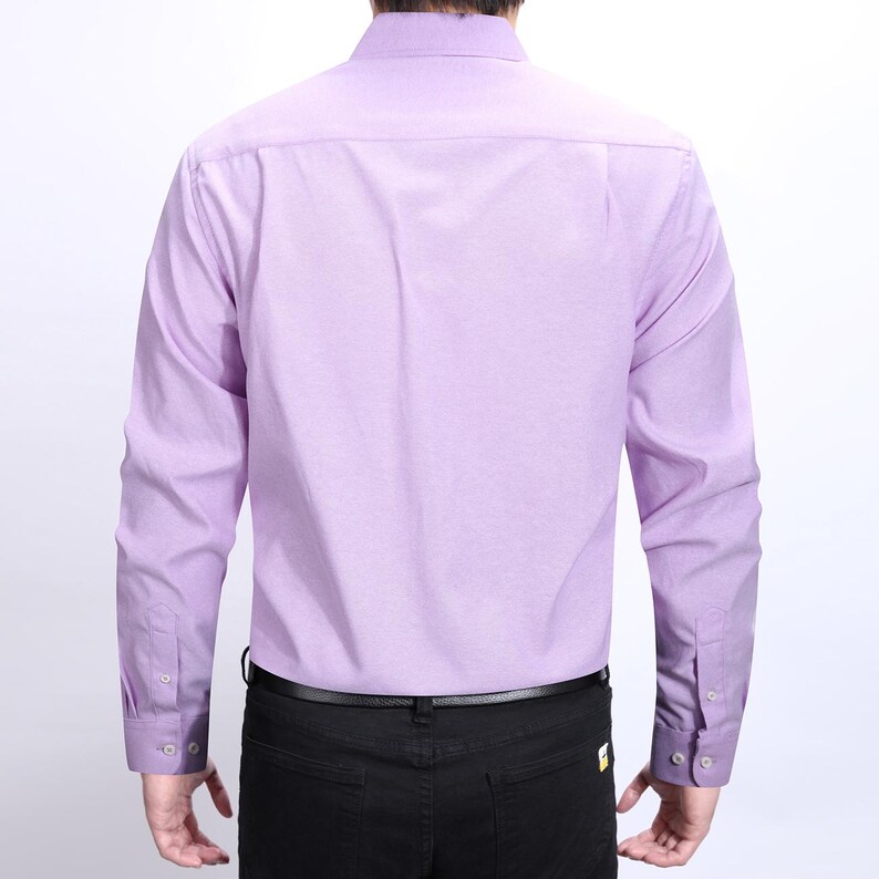 Puede incluir: Una camisa lila de manga larga con pu&ntilde;os abotonados. La camisa se combina con pantalones negros y un cintur&oacute;n negro. La vista trasera de la camisa muestra el cuello y los pu&ntilde;os abotonados.