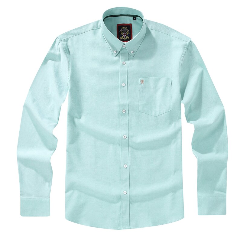 Puede incluir: Una camisa de manga larga en color verde menta claro con cuello abotonado, un bolsillo en el pecho con un peque&ntilde;o emblema bordado y una tapeta central con botones blancos. La prenda presenta un tejido con textura y un corte estructurado.