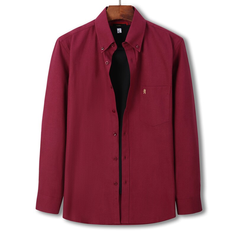 May include: A long-sleeved, button-down shirt in a deep burgundy hue. The shirt has a button-down collar, a chest pocket with a small gold emblem, and a classic fit. It is displayed on a wooden hanger.