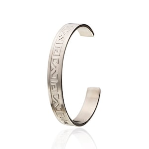May include: A silver bracelet with a geometric pattern engraved around the band.