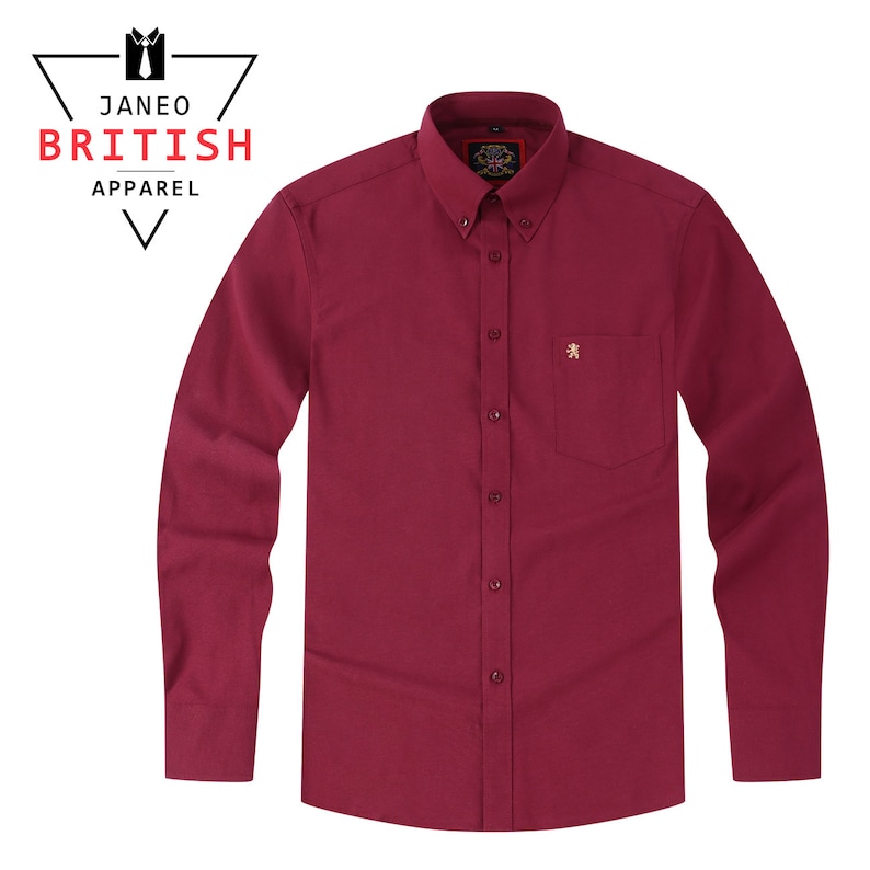 May include: A long-sleeved, button-down shirt in a rich burgundy hue. The shirt has a button-down collar, a chest pocket, and a small embroidered lion emblem. The text "JANEO BRITISH APPAREL" is visible in the upper left corner.