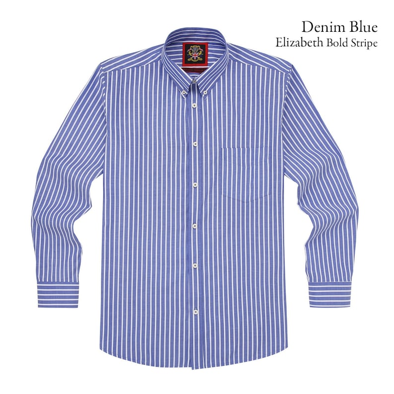 Op de afbeelding: Denim blauw overhemd met lange mouwen en witte verticale strepen. Het overhemd heeft een button-down kraag, een borstzak en een label met de tekst "Elizabeth Bold Stripe".