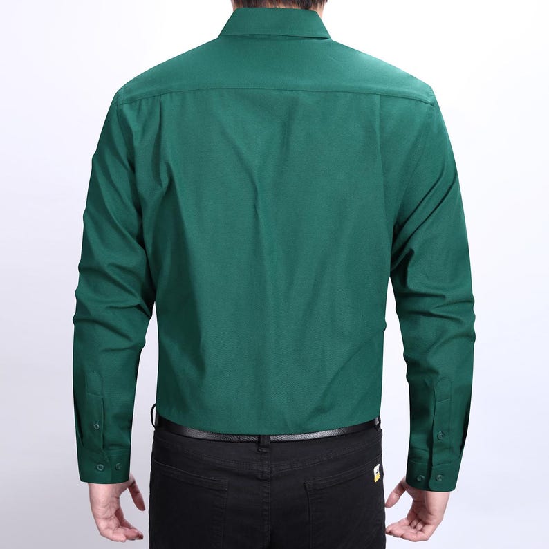 Peut inclure: Chemise &agrave; manches longues vert &eacute;meraude unie avec col boutonn&eacute;. La chemise a des poignets boutonn&eacute;s et est port&eacute;e avec un pantalon noir et une ceinture noire. Vue arri&egrave;re de la chemise.