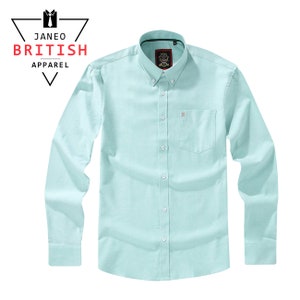 May include: A light blue button-down shirt with long sleeves and a chest pocket. The shirt has a small embroidered logo on the pocket and the brand name "JANEO BRITISH APPAREL" is displayed in the upper left corner.