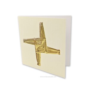 May include: A gold Celtic cross card with a white background. The cross is made of woven straw and has a gold metallic finish. The card has the website "worldprayergifts.com" printed on the bottom.