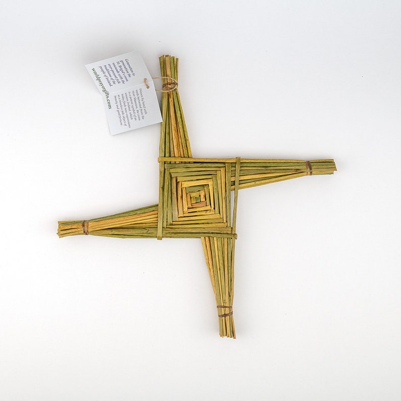 May include: A woven straw Celtic cross, also known as a St. Brigid's Cross, with a square center. The cross is made of natural colored straw and is tied together with twine.