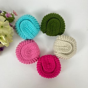 May include: Five crocheted mini bags in different colors: light blue, pink, green, white, and hot pink. The bags are all the same size and shape, and they are arranged in a circle.