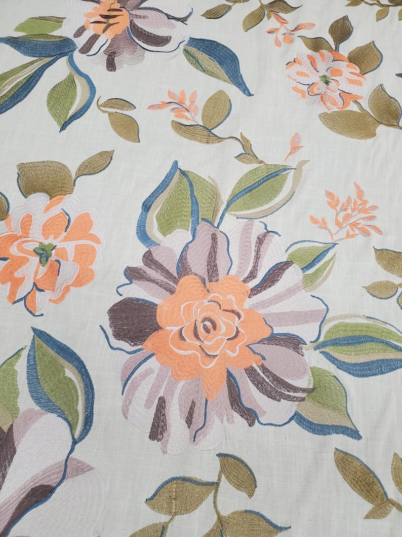 May include: A beige fabric with an embroidered floral pattern. The flowers are in shades of orange, brown, and pink. The leaves are green and blue.