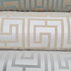 May include: Three fabric samples with a geometric pattern. The top sample is beige with a teal blue pattern. The middle sample is white with a beige pattern. The bottom sample is white with a gray pattern.