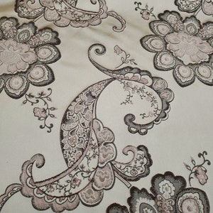 May include: A beige fabric with a paisley pattern in shades of brown and pink. The fabric has a textured, woven look.
