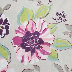 May include: A close-up of a floral fabric with a large pink and purple flower with green and blue leaves. The fabric has a light beige background.