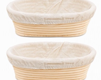 May include: Two oval-shaped proofing baskets made of light-colored natural rattan cane. Each basket features a removable, off-white fabric liner that covers the interior and folds over the top rim, creating a clean and structured appearance.