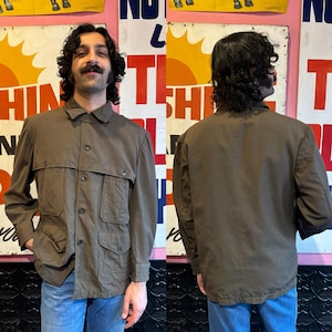 Könnte beinhalten: Eine braune Utility-Jacke mit mehreren Taschen und einem Knopfschloss vorne. Die Jacke wird von vorne und hinten gezeigt.