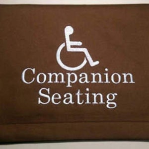 May include: Brown fabric seat cushion with a white wheelchair symbol and the text "Companion Seating" embroidered on it.