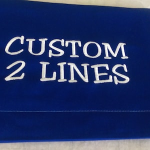 May include: A royal blue fabric pouch with white embroidery that reads "CUSTOM 2 LINES".