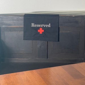 May include: A black sign with white text that reads "Reserved" and a red plus sign.