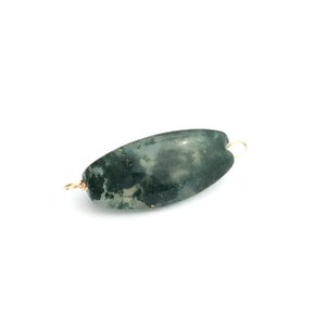 May include: A green moss agate bead with gold-toned wire loops on either end. The bead is oval shaped and has a mottled green and white pattern.