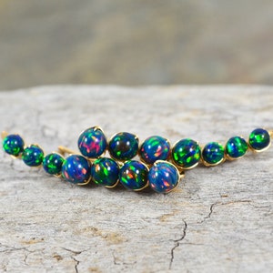 Puede incluir: Un par de pendientes de oro con un racimo de cuentas de ópalo azul y verde iridiscentes.