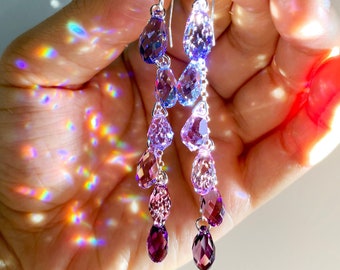 Può includere: Un paio di orecchini pendenti con un gradiente di cristalli a forma di goccia di colore viola e rosa.